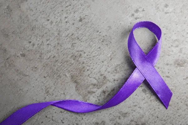 Cinta púrpura sobre fondo de piedra gris, vista superior. Sensibilización sobre violencia doméstica — Foto de Stock
