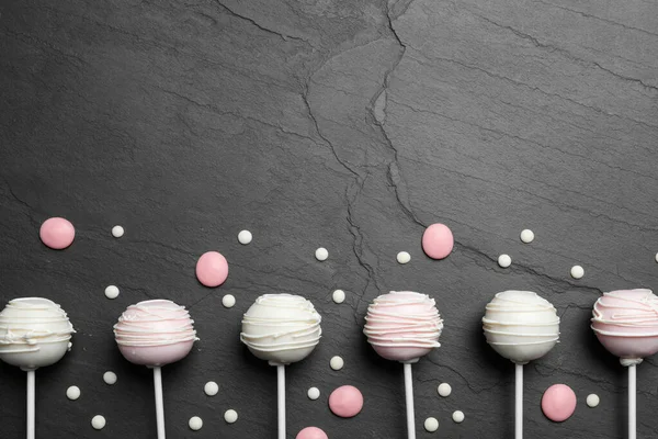 Flat lay composition with sweet cake pops on black background. Space for text