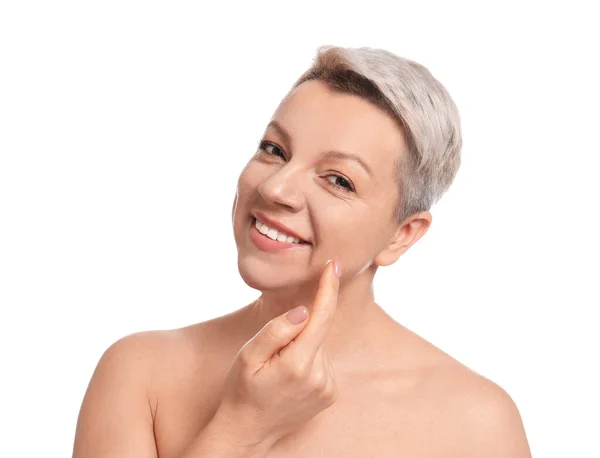 Mujer madura aplicando crema facial sobre fondo blanco —  Fotos de Stock