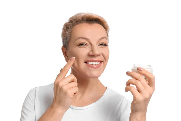 Mujer madura aplicando crema facial sobre fondo blanco —  Fotos de Stock