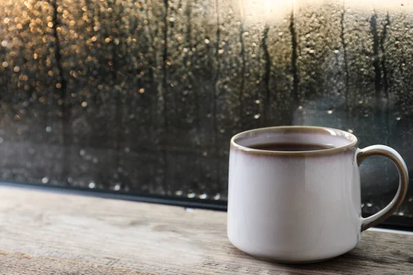 Una taza de té caliente en un alféizar de madera. espacio para el texto. Clima lluvioso — Foto de Stock