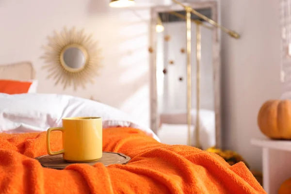 家でオレンジブランケットでベッドの上で熱い飲み物。秋の色の装飾のアイデア — ストック写真