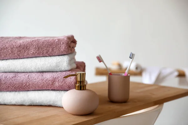 Stack of clean soft towels, soap dispenser and toothbrushes in bathroom — ストック写真