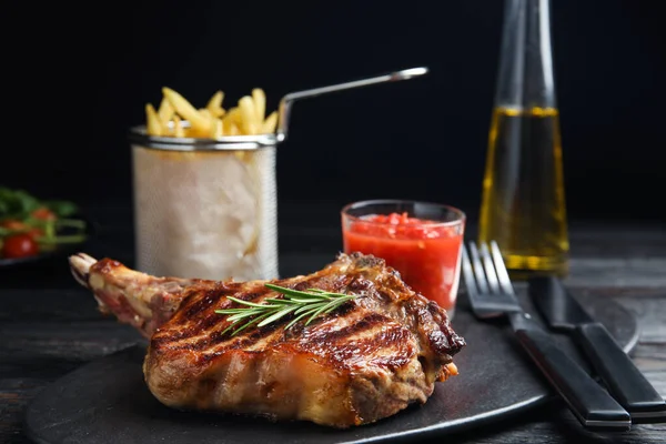 Bife grelhado saboroso na mesa de madeira preta — Fotografia de Stock