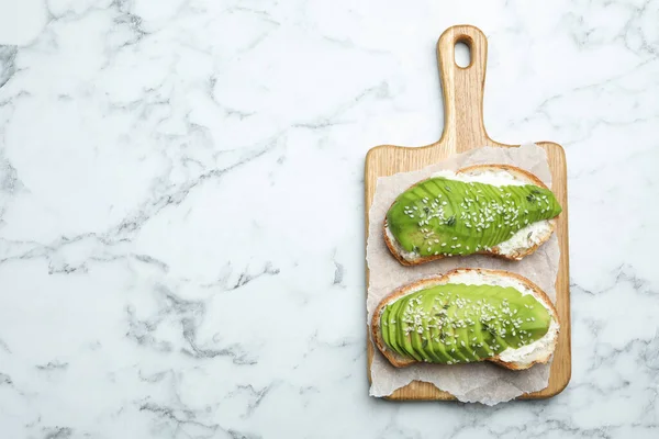 Lekkere avocado sandwiches op witte marmeren tafel, bovenaanzicht. Ruimte voor tekst — Stockfoto