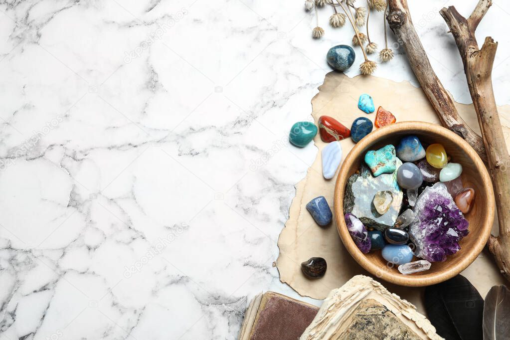 Flat lay composition with different gemstones on white marble background. Space for text