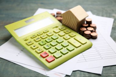 Bozuk paralar, belgeler ve hesap makineli ev modeli, ahşap masa, yakın plan. Emlakçılık hizmeti
