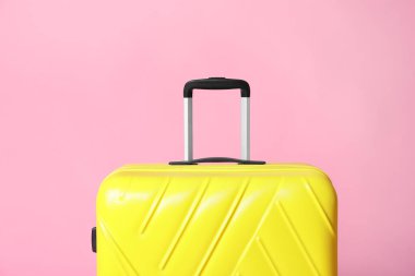 Açık pembe arka planda modern sarı bavul