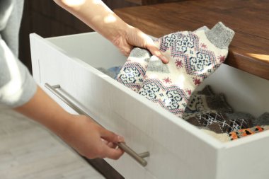 İçerideki çekmeceden sıcak örülmüş çorapları çıkaran kadın, yakın plan.