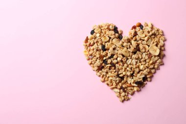 Pembe arka planda ev yapımı sağlıklı granola çikolatalarından yapılmış kalp düzleştirilmiş. Metin için boşluk