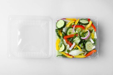 Beyaz arka planda taze salata ile plastik kap, üst görünüm