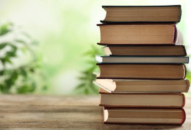Ahşap masanın üzerinde arka planda bulanık duran bir yığın kitap. Metin için boşluk