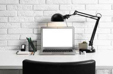 Laptop ve lambalı modern işyeri tuğla duvarın yanında. Tasarım için boşluk