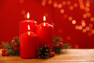 Bulanık ışıklara karşı ahşap masada yanan mumlarla güzel bir Noel kompozisyonu. Metin için boşluk