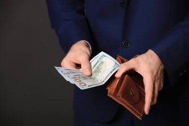 Cüzdanı olan bir iş adamı ve siyah arka planda dolar banknotları, yakın plan