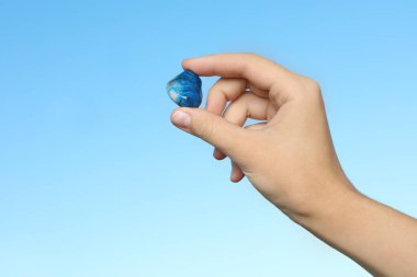 Mavi arka planda Shattuckite mücevheri tutan kadın, yakın plan.