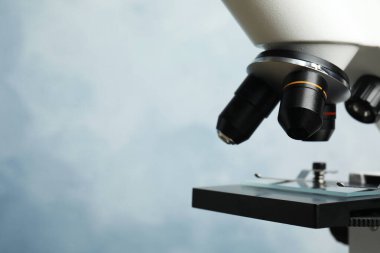 Modern mikroskobun mavi arkaplandaki yakın görüntüsü, metin için boşluk. Tıbbi ekipman
