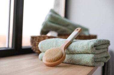 Clean soft towels and shower brush on windowsill in bathroom