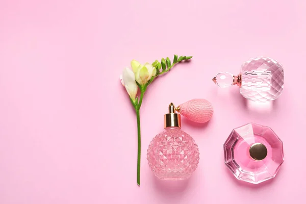 Platte lay compositie met parfumflesjes en bloemen op lichtroze achtergrond, ruimte voor tekst — Stockfoto