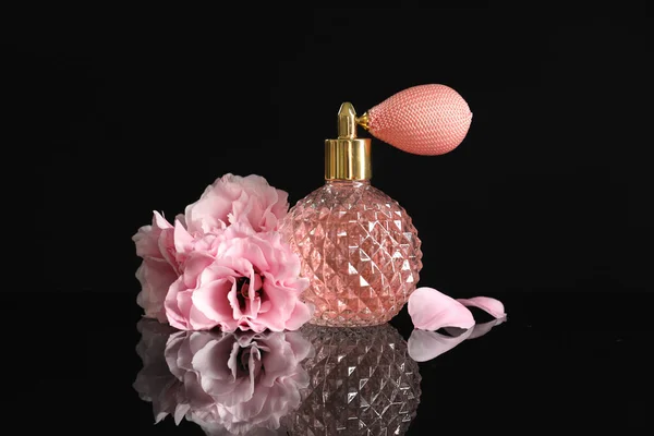 Garrafa vintage de perfume e belas flores no fundo preto — Fotografia de Stock