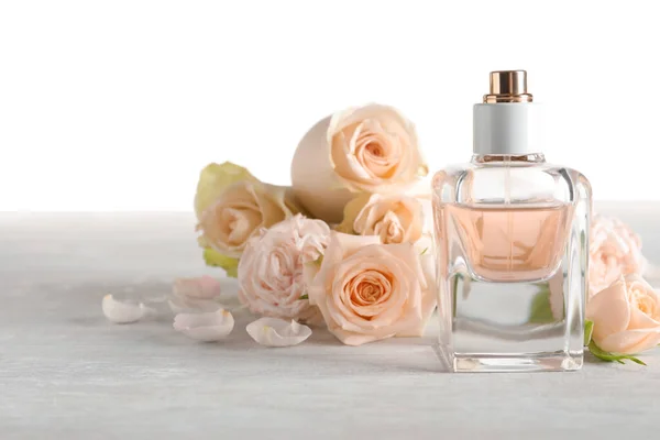 Elegante bottiglia di profumo e fiori su sfondo chiaro, spazio per il testo — Foto Stock