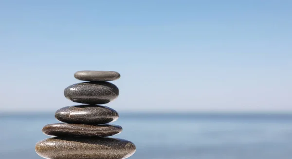 Montón de piedras contra el paisaje marino borroso, espacio para el texto. Concepto zen — Foto de Stock