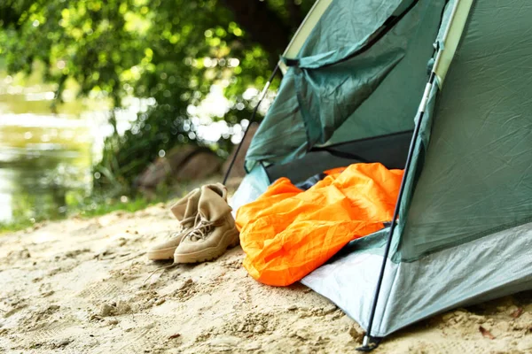 Палатка для кемпинга с спальным мешком и сапогами на пляже — стоковое фото
