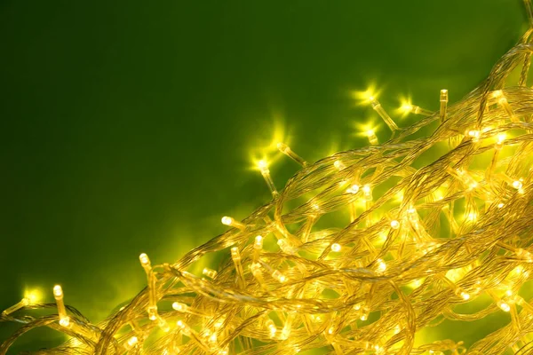 Luces brillantes de Navidad sobre fondo verde, vista superior. Espacio para texto — Foto de Stock