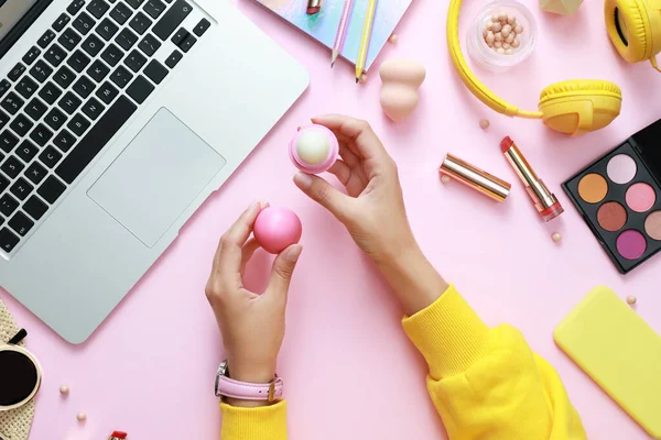 Joven blogger de belleza con bálsamo labial cerca de laptop y accesorios sobre fondo rosa claro, vista superior — Foto de Stock