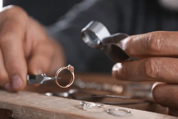 Ювелир осматривает бриллиантовое кольцо в мастерской, вид крупным планом — стоковое фото