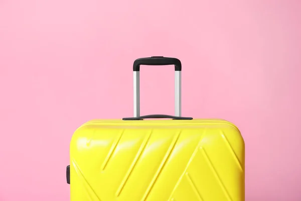 Moderner gelber Koffer auf hellrosa Hintergrund — Stockfoto