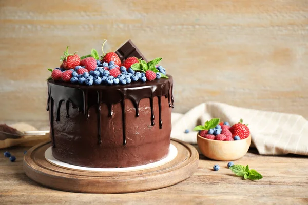 Frisch zubereiteter leckerer Schokoladenkuchen mit Beeren auf Holztisch — Stockfoto