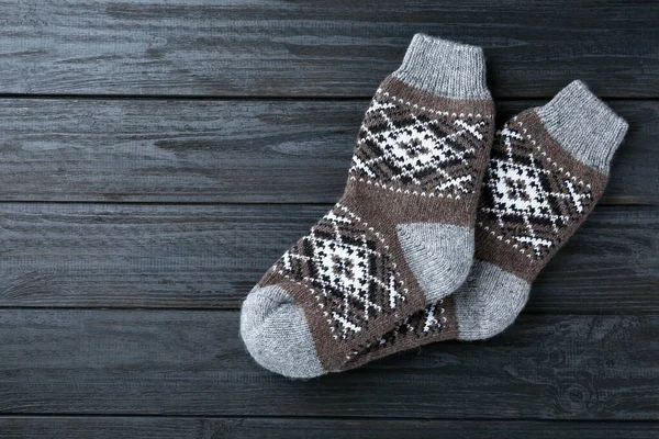Warm knitted socks on black wooden background, flat lay. Space for text — Stock Photo, Image