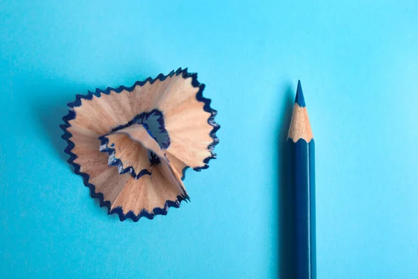 Color pencil and shaving on blue background, top view — Stock fotografie