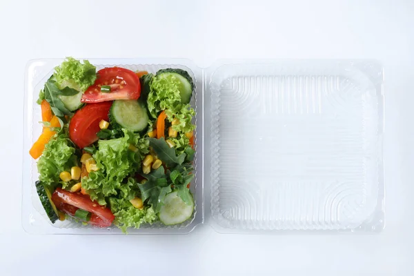 Plastic container with fresh salad on white background, top view