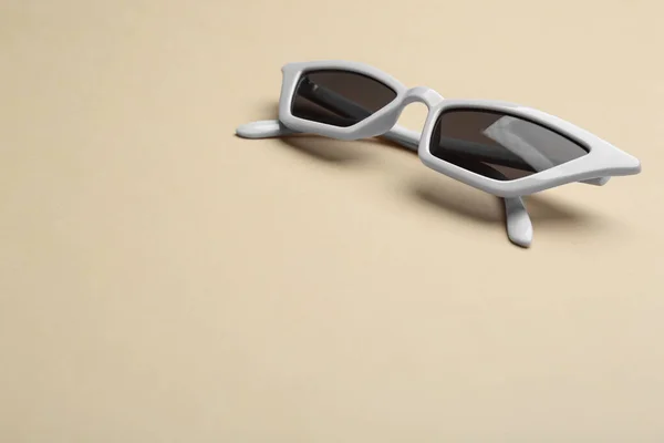 Óculos de sol elegantes em fundo bege, espaço para texto. Acessório na moda — Fotografia de Stock