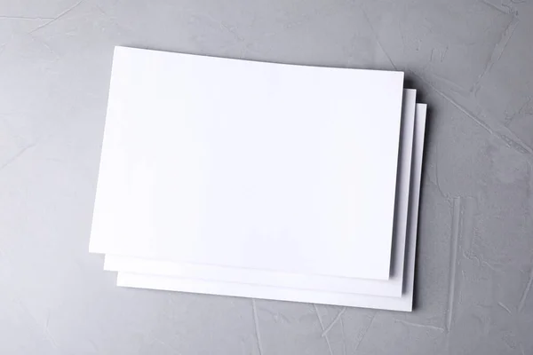 Hojas de papel en blanco sobre fondo de piedra gris claro, vista superior. Prepárate para el diseño —  Fotos de Stock