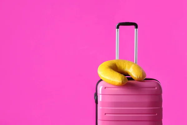 Walizka i żółta poduszka podróżna na różowym tle, miejsce na tekst — Zdjęcie stockowe