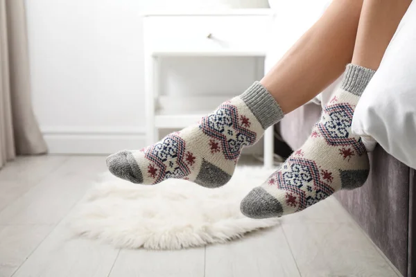 Woman wearing knitted socks on bed indoors, closeup. Warm clothes — Stock Photo, Image