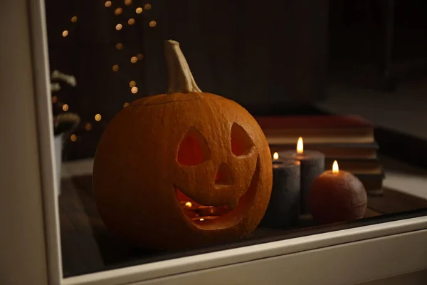 Composição com cabeça de abóbora no peitoril da janela, vista através de vidro. Lanterna de Jack - decoração de Halloween tradicional — Fotografia de Stock