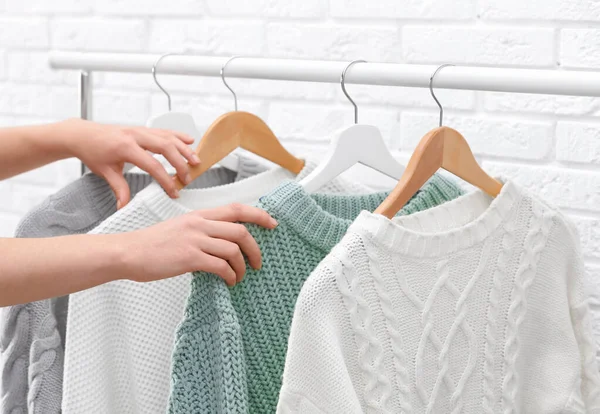 Mujer elegir suéter en rack cerca de la pared de ladrillo, primer plano —  Fotos de Stock