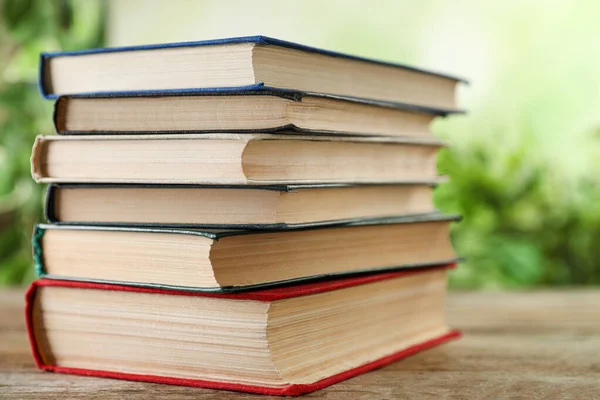 Stapel hardcover boeken op houten tafel tegen wazige achtergrond — Stockfoto