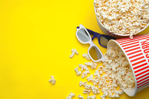 3D glasses and popcorn on yellow background, flat lay with space for text. Cinema snack