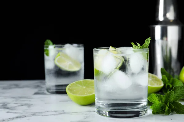 Bicchiere di cocktail con vodka, ghiaccio e lime su tavolo in marmo bianco su sfondo nero. Spazio per testo — Foto Stock