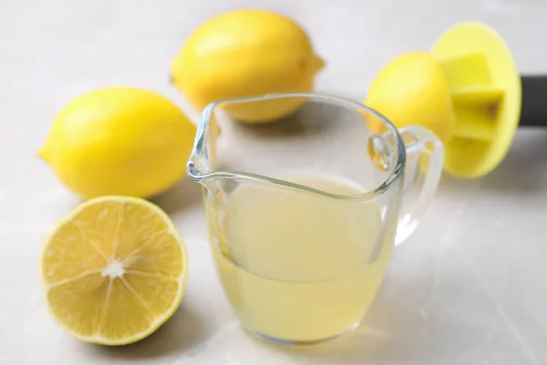 Čerstvě vymačkaná citrónová šťáva na světlém stole — Stock fotografie