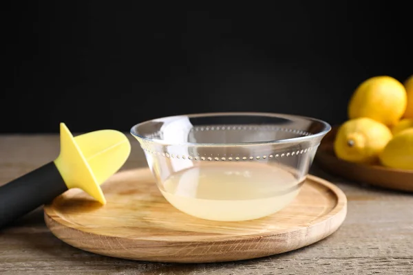 Jus de citron fraîchement pressé et alésoir sur table en bois — Photo