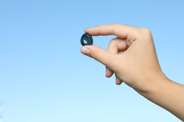 Женщина держит драгоценный камень на синем фоне, крупным планом. Пространство для текста
