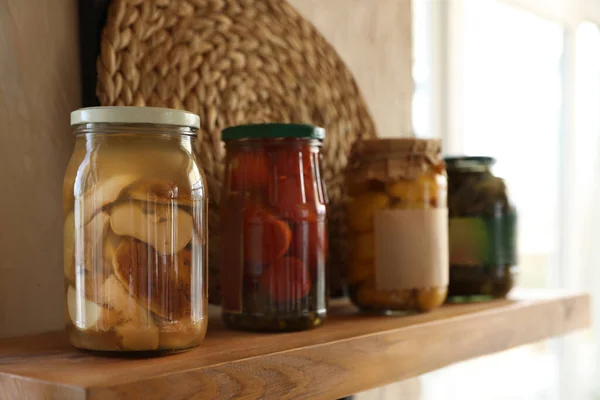 Canned foods on wooden shelf in modern kitchen — Stock Photo, Image