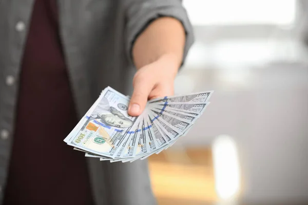 Muž s americkými penězi na rozmazaném pozadí, detailní záběr — Stock fotografie