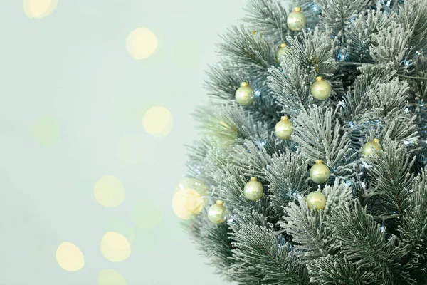 Mooie kerstboom en wazig feestelijk licht op lichte achtergrond. Ruimte voor tekst — Stockfoto